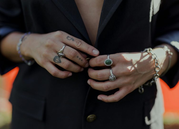 Hands adorned with rings, bracelets, and tattoos, showcasing style and elegance.