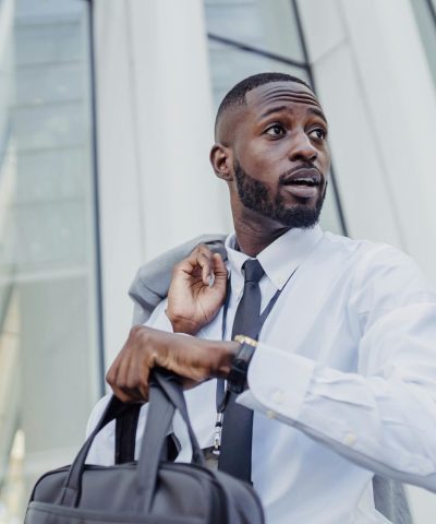 A professional businessman with a bag adjusting his tie outdoors.