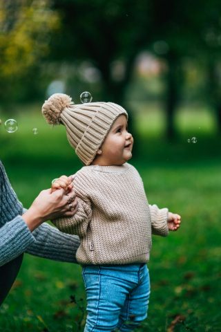 A joyful moment with mother and child playing with bubbles outdoors in a park.