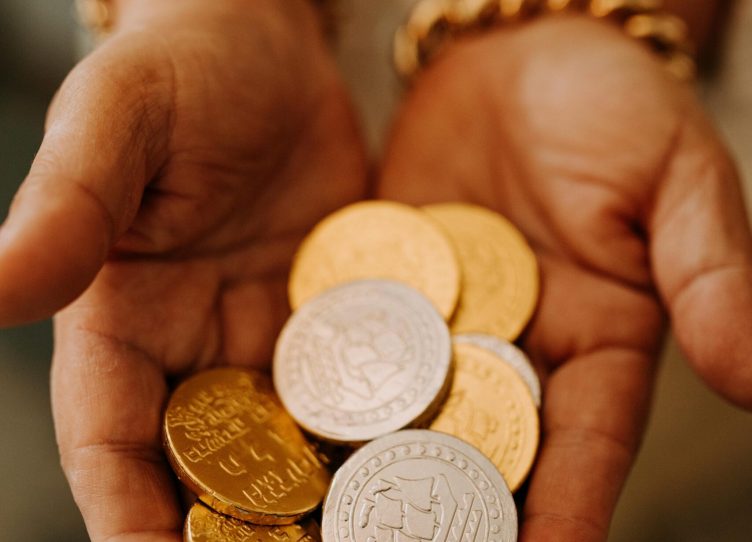 Close-up of hands holding golden and silver Hanukkah gelt coins, symbolizing tradition.